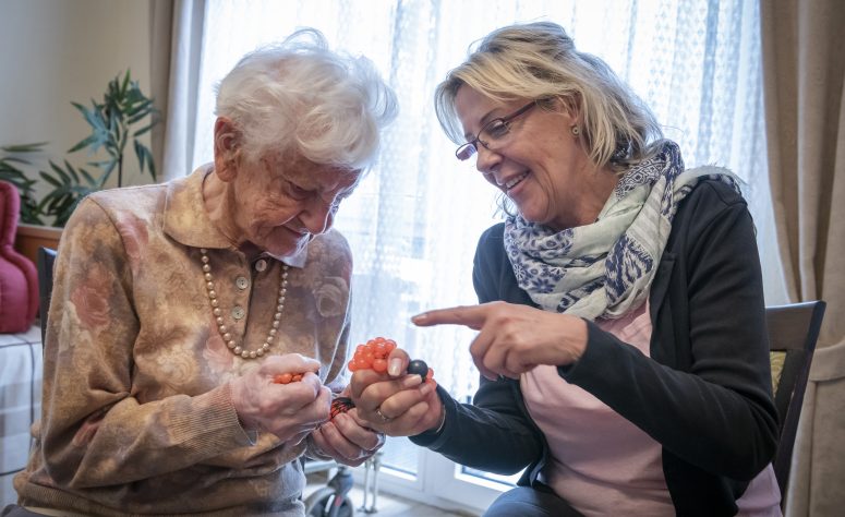 Pflegerin trainiert Handmuskulatur mit einer Dame