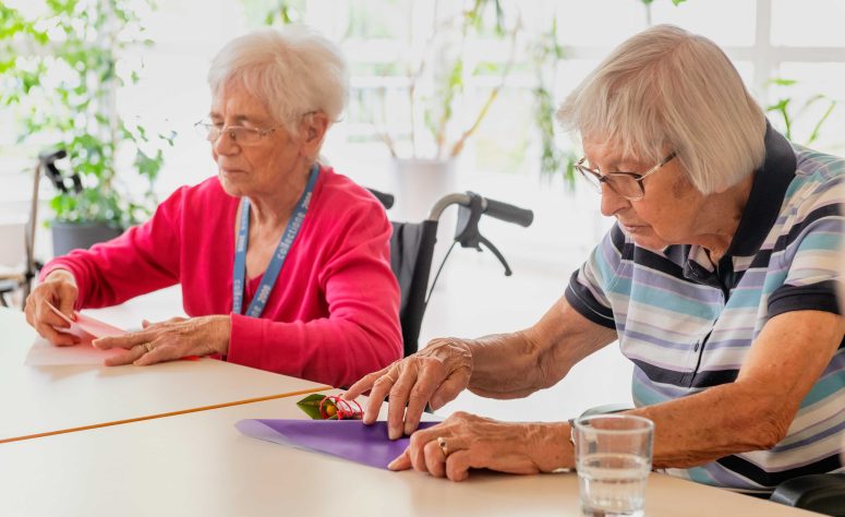 Zwei Omas sind konzentriert beim Falten eines Papieres